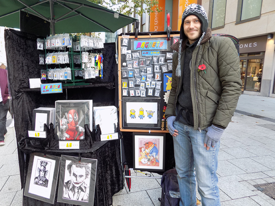 Artist Tudley James smiles wide while showcasing his art in the city centre
