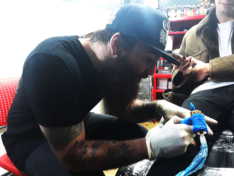 Aaron tattooing a a coffee cup onto a kneecap