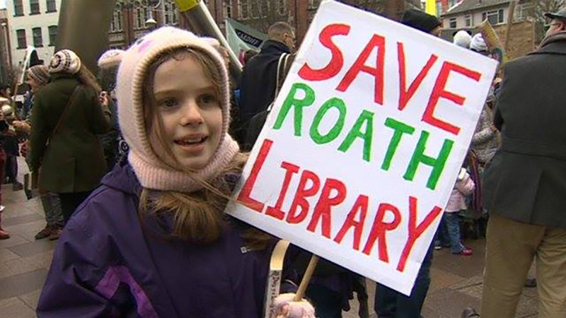 a child holds up a sign to save Roath Library