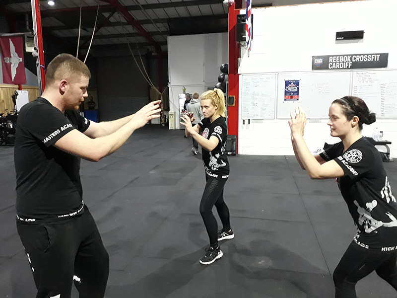 two women and a man are in a self-defence class