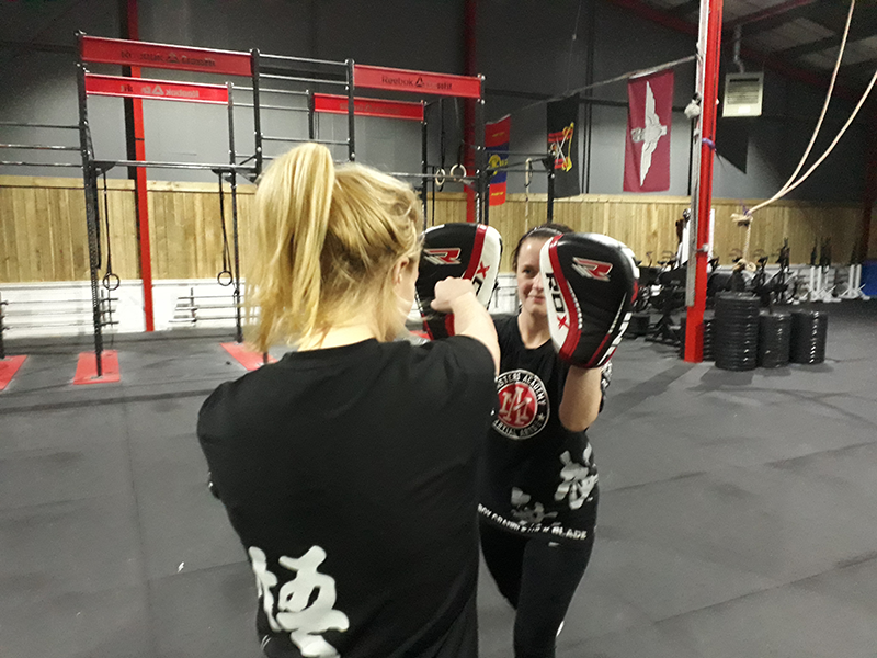 A woman is punching pads held by another woman