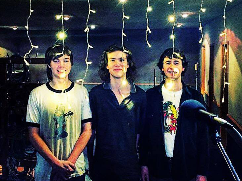 Three boys standing behind fairy lights