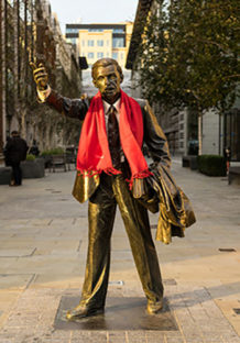 A red Wrap Up scarf is draped around a statue in London