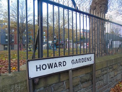 A picture of the Howard Gardens green space sign with the park in the background