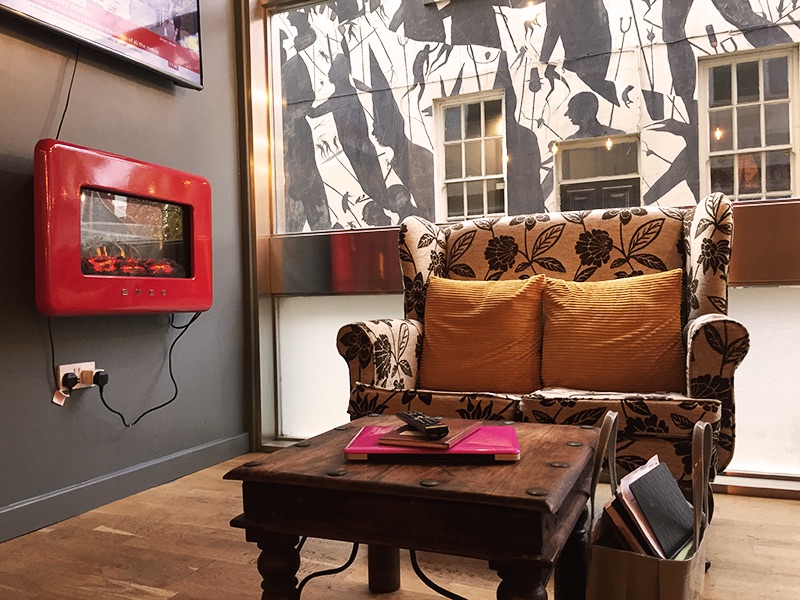 white and black floral armchair with yellow pillows on cafe next to fireplace