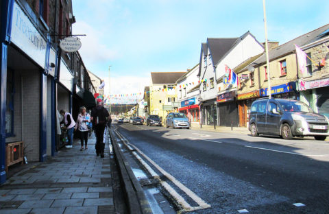 Treorchy high Street on a Saturday, showing shoppers and shop fronts, and flags and bunting