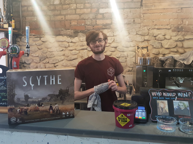 Mike stands at the bar with a board game he played recently