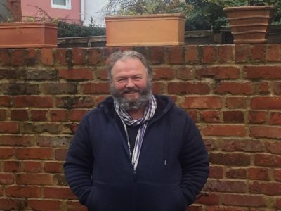 Kieth Munro smiling in front of a brick wall