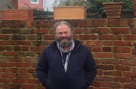 Kieth Munro smiling in front of a brick wall