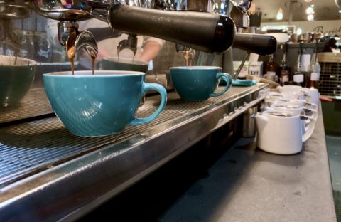 Row of blue coffee cups under espresso machine