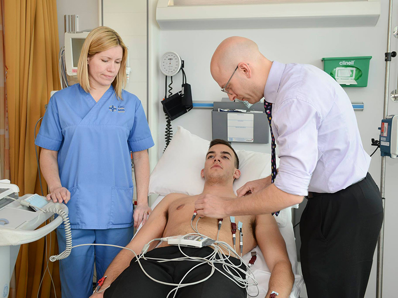 A man having a heart scan with a doctor and a nurse.