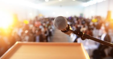 Microphone in front of podium with crowd in the background