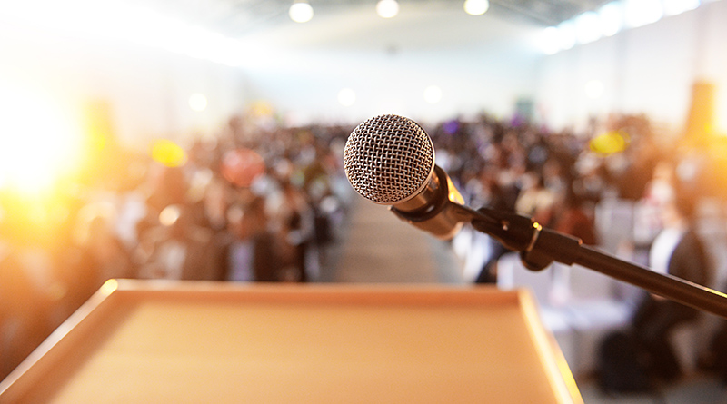 Microphone in front of podium with crowd in the background