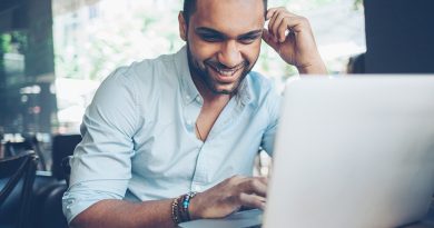 Smiling young man working on a laptop in cafe.