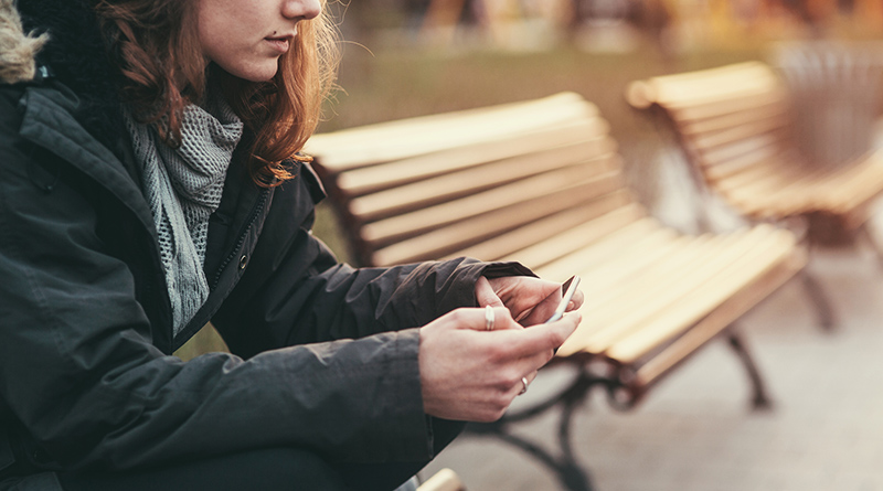 Teenage girl feeling depressed, using a smartphone