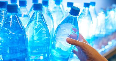 Human hand taking mineral water from shelf in supermarket