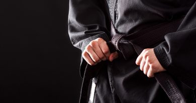 Closeup of male karate fighter tying the knot to his black belt