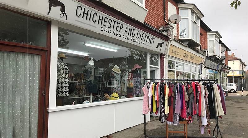 A high-street charity shop with clothes hangling on a rail outside